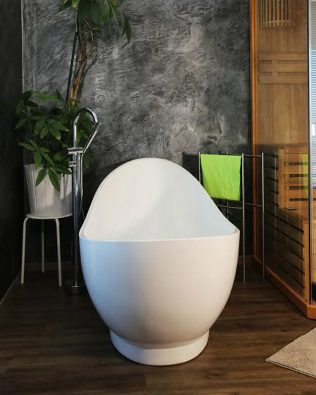 Modern freistehende Badewanne in Ei-Form in stilvollem Badezimmer mit dunklem Holzboden, Pflanze und Handtuchständer.